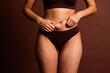 © deagreez - Cropped photo of plus size pretty lady underwear doing tummy massage isolated brown color background