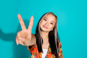 Poster - Photo of happy lovely cute girl wear trendy print clothes demonstrate v-sign isolated on cyan color background