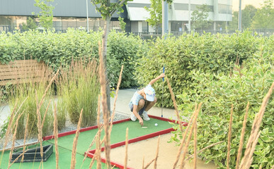 Wall Mural - teenage girls play mini golf on the course. 