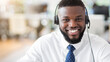 © Prostock-studio - A customer service representative wearing a headset smiles broadly while sitting at a desk in an office.
