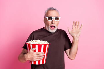 Poster - Portrait of astonished man with beard dressed t-shirt in 3d glasses hold pop corn watch horror movie isolated on pink color background