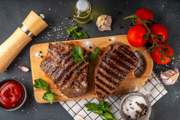 Wall Mural - Grilled beef steak on wooden cutting board with ketchup sauce and condiments, top view copy space