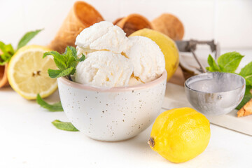 Sour sweet lemon sorbet ice cream, refreshing tasty lemon gelato dessert with fresh lemons, mint and waffle ice cream cones, white table background copy space