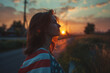 © Rattanapon - American female wrapped in national USA flag at sunset background.
