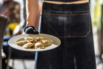 Wall Mural - The waiter is holding a plate with traditional Slovak pirogi - pirohy. Polish pierogi. Ukrainian verenyky