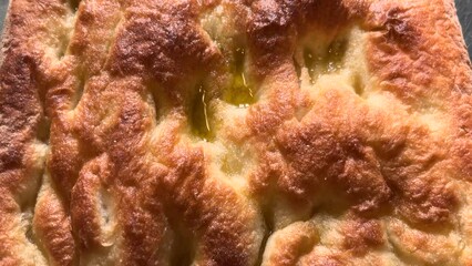 Wall Mural - Focaccia with extra virgin olive oil, typical flat bread of Genoa, slide shot in top view