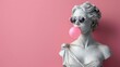 © alphaspirit - Vintage statue with white shades blowing pink bubble gum against a pink backdrop