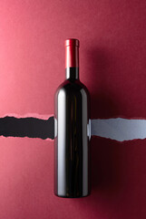 Wall Mural - Bottle of red wine on a dark red background.