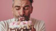 © Z A C - Man with closed eyes enjoying a bite of a chocolate cake with pink frosting and sprinkles.