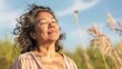© iuricazac - A woman with closed eyes smiling and enjoying the breeze in a field of tall grass under a blue sky.
