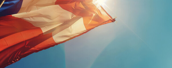 Wall Mural - Bastille Day background with a close-up of a tricolor flag waving in the wind against a clear blue sky.