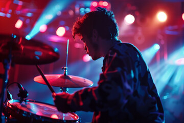 Wall Mural - A man playing drums in a dark room with bright lights