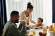 © LIGHTFIELD STUDIOS - A loving African American family enjoying a meal together at a table.