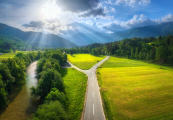Wall Mural - aerial view of road in green meadows at sunset in summer. top view from drone of rural road, river, 