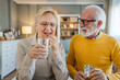 © Miljan Živković - senior couple at home woman take medicine while her husband sit beside