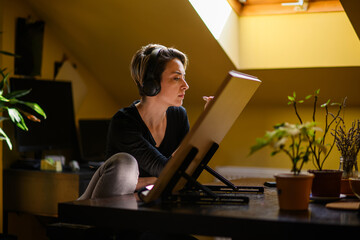 Side view of a creative artist enjoying music and pencil drawing at home