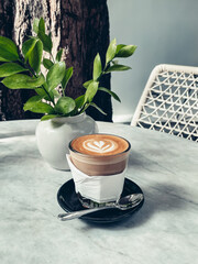 Wall Mural - A glass of coffee with latte art on top on marble table