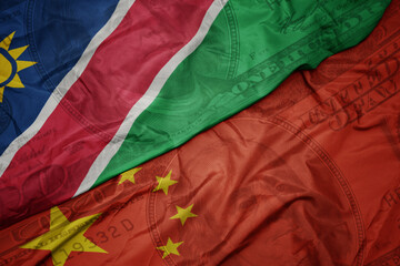 Wall Mural - waving colorful flag of namibia and national flag of china on the dollar money background. finance concept.
