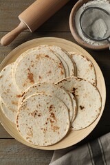 Wall Mural - Many tasty homemade tortillas and rolling pin on wooden table, top view