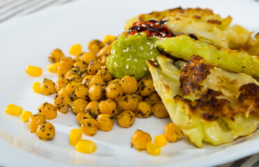 Wall Mural - Delicious cabbage in batter served with garnish of braised chickpeas and two sauces on white plate