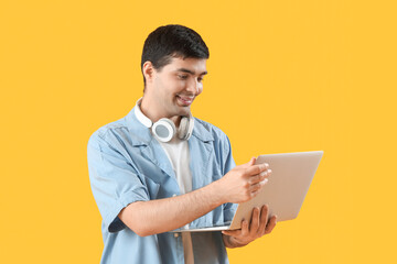 Male programmer working with laptop on orange background