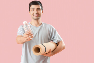 Sticker - Sporty young man with bottle of water and fitness mat on pink background