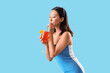 © Pixel-Shot - Beautiful young Asian woman drinking tasty aperol spritz cocktail on blue background
