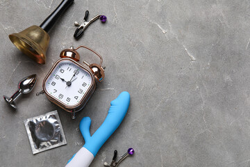 Wall Mural - Alarm clock with different toys and condom on grunge grey background. Time for sex