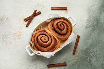 Wall Mural - Baking dish with tasty cinnamon rolls on grunge background