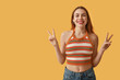 © Pixel-Shot - Pretty young woman showing peace gestures on orange background