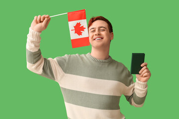 Wall Mural - Handsome young happy man with Canadian flag and passport on green background