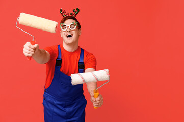 Sticker - Portrait of cheerful male painter in Christmas reindeer headband with rollers on red background