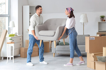 Wall Mural - Happy young couple carrying armchair in room on moving day