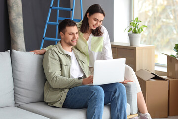 Wall Mural - Young couple using laptop in room on moving day