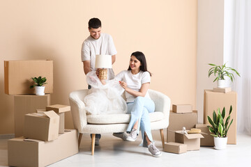 Wall Mural - Young happy couple unpacking belongings on sofa in their new house