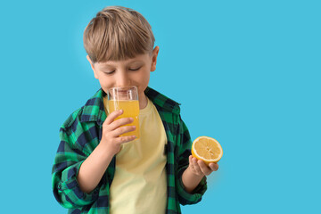 Poster - Cute little boy with lemon and glass of lemonade on blue background