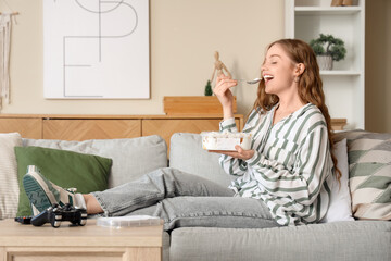 Wall Mural - Young woman eating ice cream on sofa at home