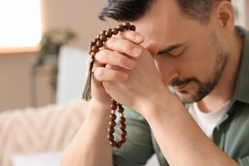 Poster - Religious man with beads praying at home, closeup