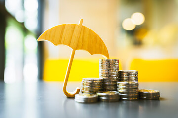 Wall Mural - Model of umbrella and coins on wooden table concept of the system of insurance savings and the cost of health insurance