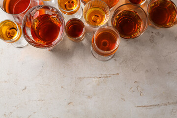 Wall Mural - Different delicious liqueurs in glasses on light grey table, flat lay. Space for text