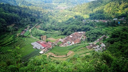 beautiful village view at the foot of mountains and hills with blue sky and white clouds