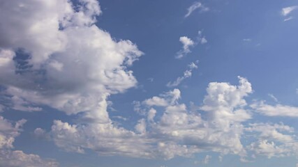 Wall Mural - Fluffy white clouds drift across a bright blue sky on a sunny day, timelapse