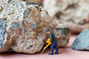 Wall Mural - A miniature worker worker drilling a big rock . Themes of perseverance, strength and labor. This makes it suitable for use in content that involves hard work, challenges, and overcoming obstacles.