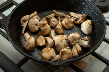 Wall Mural - A view of a quartered button mushrooms sauteing in a cast iron skillet.