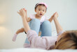© Nunkung - Young daughter plays with asian cute mother lying on the bed that mother held her daughter's hand and spread it out and imagined herself to be like an airplane enjoy flying in the air.