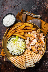Canvas Print - Turkish Doner kebab or gyros on a plate with french fries, vegetables and salad. Dark background. Top view