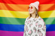 © ViDi Studio - Side profile view young smiling cheerful happy cool lesbian woman wearing pink animal clothes looking aside stand on rainbow flag background studio portrait. Pride day June month love LGBTQ concept.