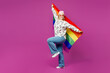 © ViDi Studio - Full body side view young happy fun lesbian woman wear pink animal clothes hold rainbow flag behind herself isolated on plain purple background studio portrait. Pride day June month love LGBTQ concept
