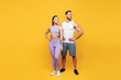 © ViDi Studio - Full body young strong fitness trainer sporty two man woman wearing blue clothes spend time in home gym stand akimbo look aside on area isolated on plain yellow background. Workout sport fit concept.