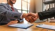 © AmolXNova - A young professional shaking hands with a new employer in an office setting.